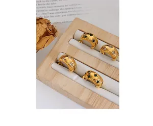 Macro shot of gold-plated Huggie earrings with inlaid white and green gemstones