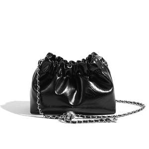 Detail of a black pleated cloud bag with shiny finish and decorative silver chain strap