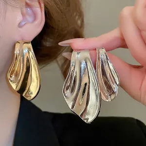 Modern gold fish-tail asymmetric earrings with abstract fluid wave texture design