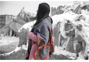 Detailed view of gray cashmere shawl with red paisley patterns and fringe edges