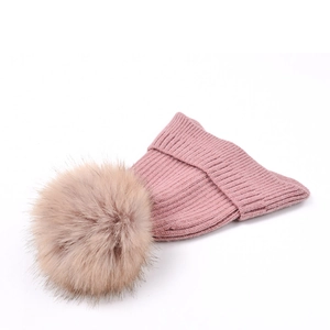 Detail of pink knit beanie with vertical texture and large faux fur pompom on top