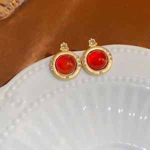 Détail de boucles d'oreilles rondes dorées avec agate rouge et halo de diamants