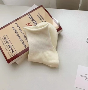 Detailed texture of off-white ribbed knit cotton socks folded on books with a cute embroidery