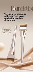 Detail of professional curved foundation brush with soft synthetic bristles and gold handle