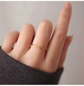Detail of slim gold titanium ring featuring three small zircon stones on a model hand