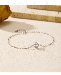Detail of silver clover bracelet with shimmering pavé diamonds on textured surface