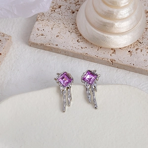 Macro shot of liquid metal earrings with purple square gemstones and silver irregular frames