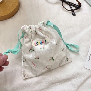 Detail of a creamy velvet drawstring storage bag with cute cartoon bears and floral prints