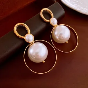 Macro detail of French vintage gold circle earrings with large white pearls on leather