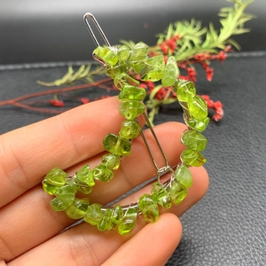 Macro shot of crescent-shaped hair clip with green natural stones on silver wire