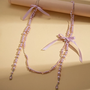 Détail du long collier en perles roses avec des nœuds et un cristal en forme de goutte
