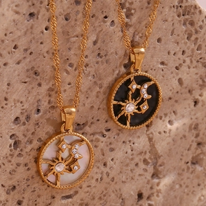 Detailed close-up of sun and moon pendant necklaces in gold with shell and enamel inlay