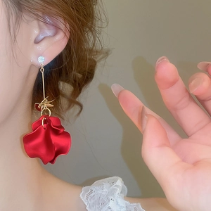 Close-up of red acrylic petal tassel earrings with gold rod and zircon stud