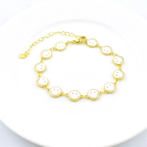 Gold plated lobster clasp bracelet with white enamel smiley face charms on ceramic plate