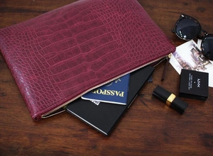 Macro view of burgundy crocodile pattern envelope clutch showing interior storage space