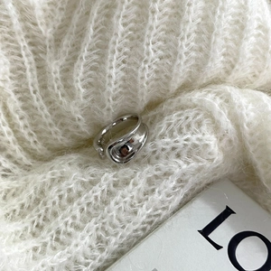 Polished silver chunky ring with abstract wavy design on white mohair knit background