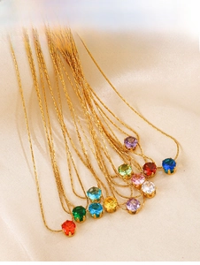 Detail of gold necklaces with colorful round claw-set zircons on champagne satin