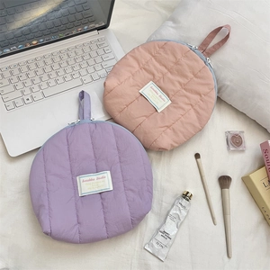 Close-up of quilted cosmetic bags with zipper handles and brand labels on white fabric