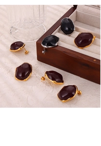 Macro shot of British style earrings set with colorful glaze inlays in a wooden jewelry box