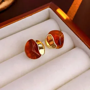 Retro geometric amber resin stud earrings with gold metal edges on white velvet display