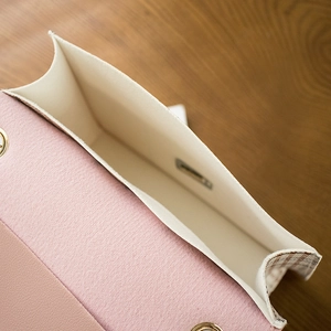 Pink leather and plaid crossbody bag showing internal compartment on wooden surface