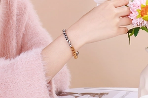 Close-up of dual-tone gold and silver box chain bracelet on a model's wrist