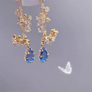 Détail macro de boucles d'oreilles papillon avec zircons et cristal goutte bleu