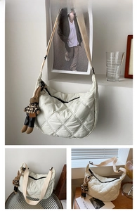 Close-up of white quilted crescent bag with diamond stitching and cute bunny charm