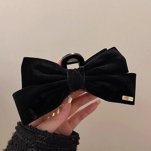 Détail d'une pince à cheveux chic en velours noir avec plaque métallique dorée