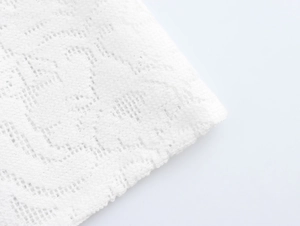 Close-up of elegant white lace fabric showing intricate floral patterns and fine mesh texture