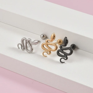 Punk snake tongue rings in silver, gold, and black colors on a white display stand
