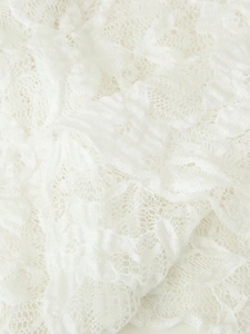 Macro shot showing detailed lace texture and white knit pattern of the feminine top