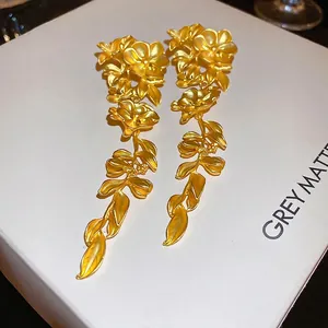Matte gold floral earrings with cascading leaf tassels on white jewelry display box