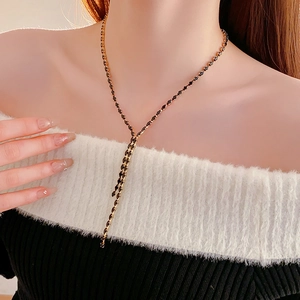 Detailed view of elegant black gemstone Y-necklace with gold accents on a model