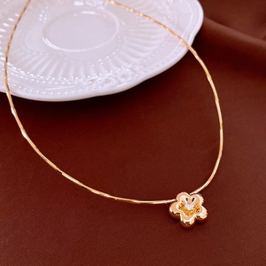 Close-up of golden flower pendant with zircon stone and elegant snake chain details