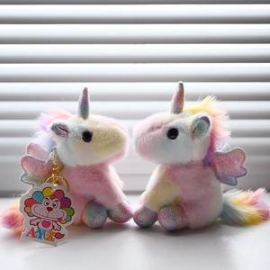 Close-up of rainbow plush unicorn keychains with glittery wings and a golden ring