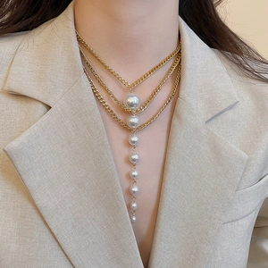 Detailed view of layered gold necklace with elegant vertical white gradient pearls on model