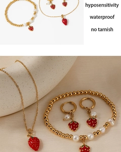 Detailansicht des goldenen Erdbeerschmucksets mit Halskette, Armband und Perlenohrringen