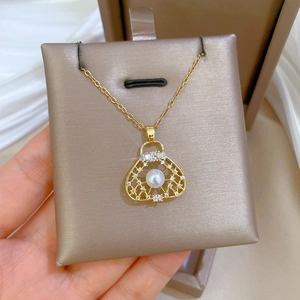 Close-up of golden titanium necklace with pearl handbag pendant and diamonds