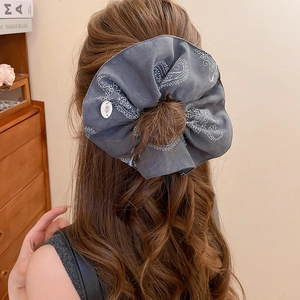 Detail of grey paisley floral scrunchie with button charm on brown wavy hair