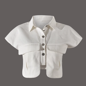 Détail d'un gilet court en jean blanc avec boutons métalliques et poches à rabat