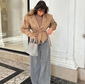 Gros plan sur la veste en daim kaki avec ceinture et jean large gris