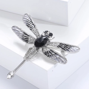 Detailed macro view of dragonfly brooch with silver metal, black crystal and white enamel