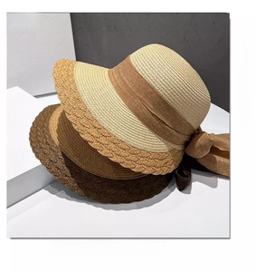 Macro detail of straw sun hat featuring wavy brim texture and elegant silk ribbon bow