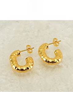 Close-up of golden C-shaped hoop earrings with unique hammered texture and butterfly back