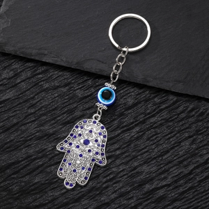 Macro detail of silver Hamsa Hand keychain with blue Evil Eye bead and crystal inlay