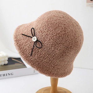 Detail of camel plush bucket hat with black bow and button on a wooden stand