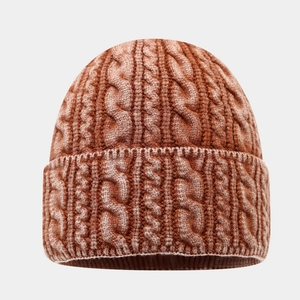 Gros plan sur la maille torsadée épaisse d'un bonnet marron avec bordure repliée chaude