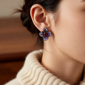 Vue macro de boucles d'oreilles fleurs vintage avec pierres rouges et mauves sur l'oreille