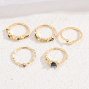 Detail of 5-piece vintage gold ring set featuring blue crystals and hollow patterns